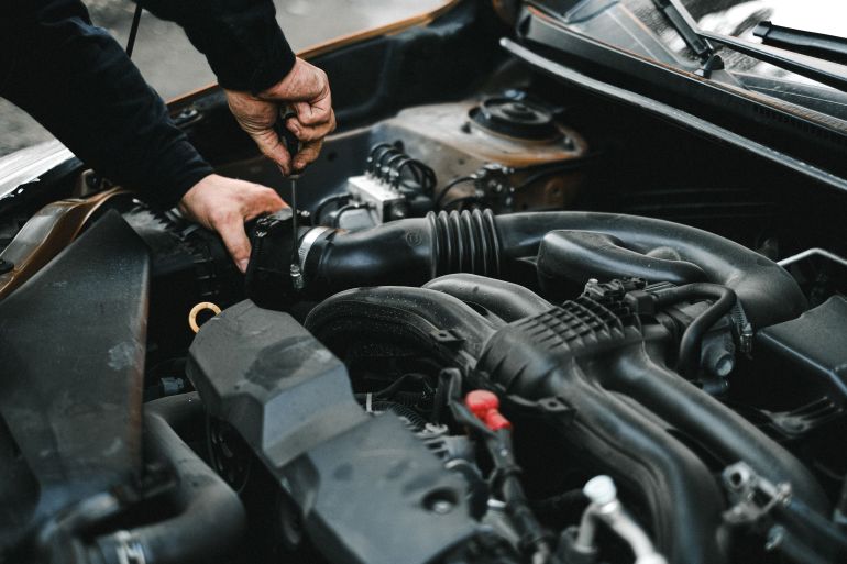 4315570-1786036581 Close-up of a mechanic working on a car engine. Ideal for auto repair themes.