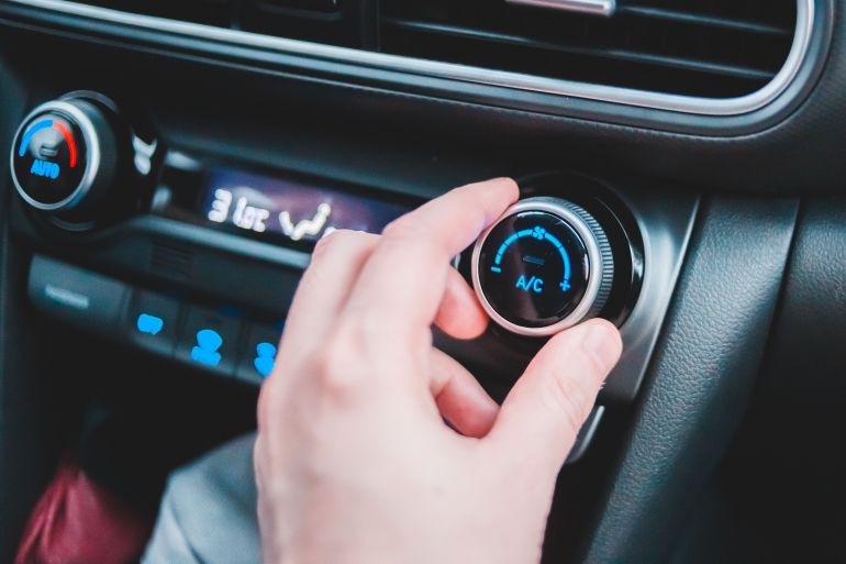 7196452-1786032477 Close-up of a hand adjusting the air conditioning settings on a modern car dashboard.