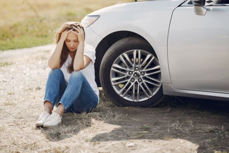 Young woman upset with car trouble, stranded roadside in rural area during summertime journey.