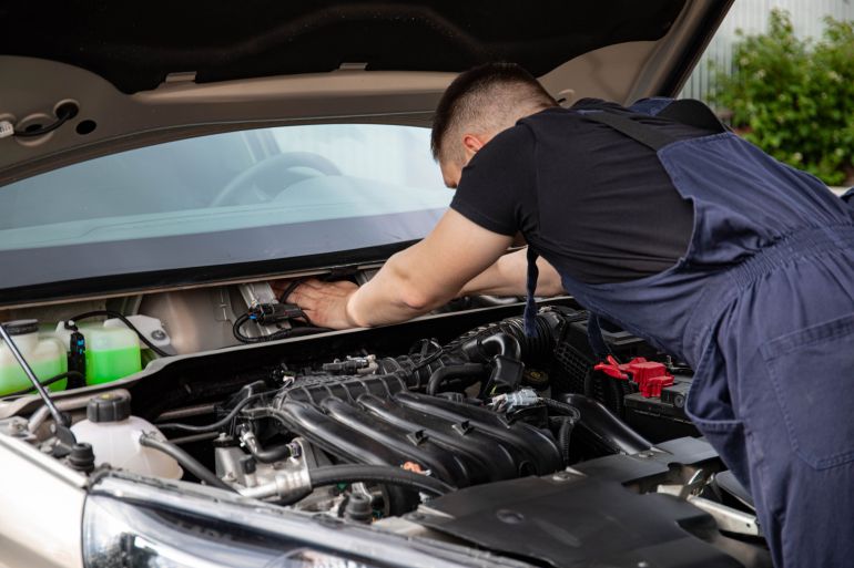 8478259-1786035412 Auto mechanic performs engine maintenance on a car. Focus on hands and engine components.