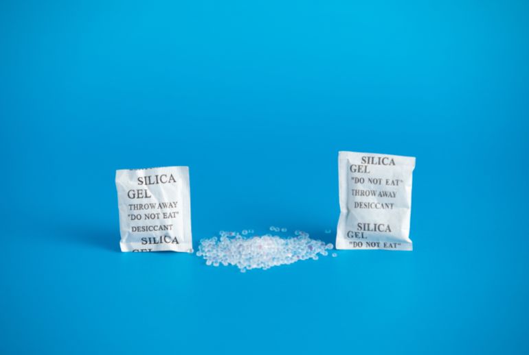 Desiccant or silica gel indifferent packaging and spread on blue background.المصدر: أدوبي ستوك