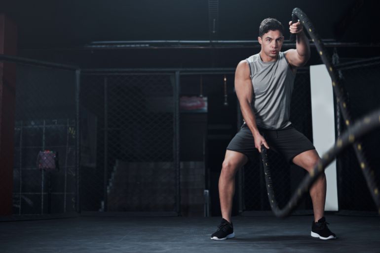 adobestock_601258211-1787402401 Fitness, battle ropes and man at the gym doing strength, cardio and challenge workout. Strong, energy and male athlete doing exercise or training with equipment for health and wellness in sports club. المصدر: أدوبي ستوك