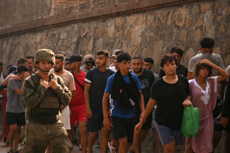 afp_6a6e2a38ec66-1785604665-1 A Spanish soldier escorts a group of migrants on their way back towards the Moroccan border, following their illegal crossing into the Spanish enclave of Ceuta, on August 1, 2026.