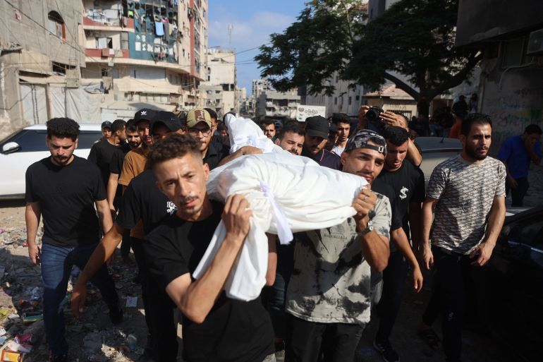 afp_6a708ce33765-1785760995 Mourners carry the shrouded body of a person killed in overnight Israeli airstrikes from the Al-Shifa Hospital in Gaza city to the cemetery on August 2, 2026.