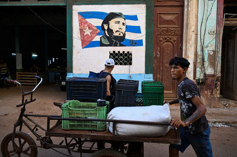 afp_6a7c111babf6-1786515739 A young man pushes his tricycle near a portrait of late Cuba's leader Fidel Castro (1926-2016) in Havana on August 10, 2026.
