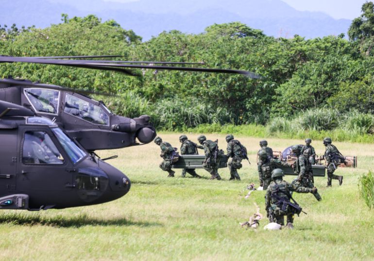 afp_6a7d5c385973-1786600504 Taiwanese soldiers carry fuel supplies towards AH-64E Apache Guardian and UH-60M Black Hawk helicopters during a refueling drill as part of the annual Han Kuang military exercise in Taoyuan on August 11, 2026. (Photo by I-Hwa Cheng / AFP)