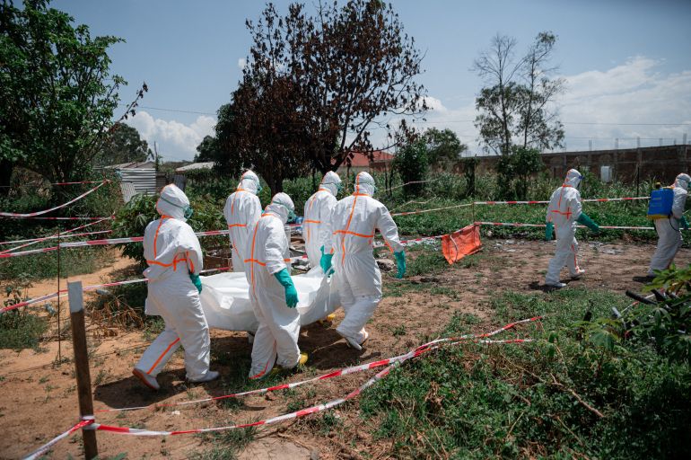 (FILES) Volunteers of the Democratic Republic of Congo Red Cross wearing personal protective equipment carry the body of an Ebola virus disease victim from the morgue of the Rwampara health centre, Ituri Province, Democratic Republic of Congo, on June 8, 2026 before loading it into a vehicle for transfer to a cemetery as part of safe and dignified burial operations aimed at preventing the spread of the virus.