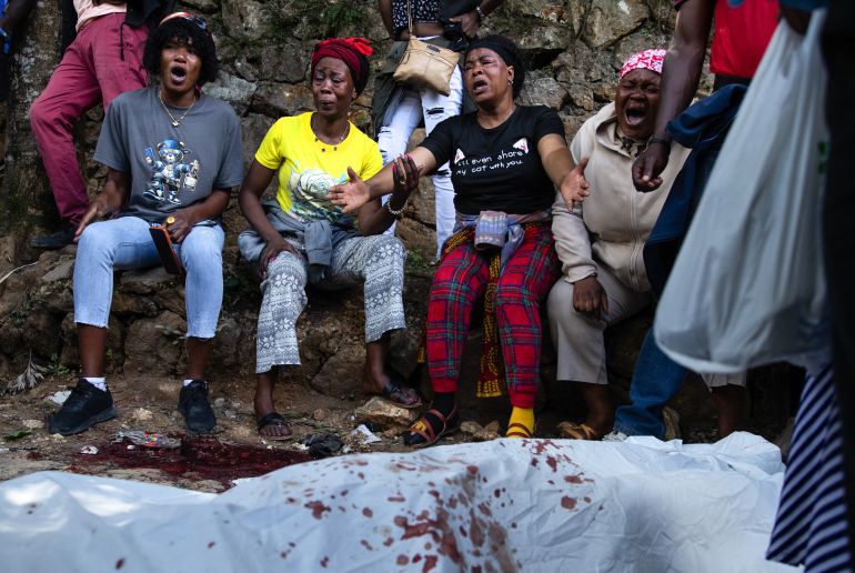 afp_6a8d01769ef1-1787625846 EDITORS NOTE: Graphic content / A body lies on the ground as people react following overnight violence where more than twenty people were killed by armed gangs in Kenscoff, a neighborhood near Port-au-Prince, Haiti, on August 24, 2026.