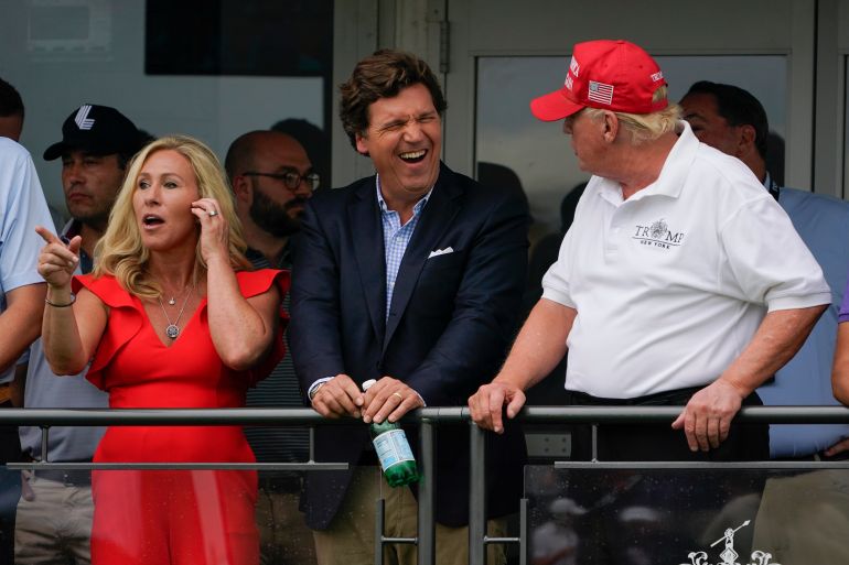 ap25064018854843-1786795537 U.S. Rep. Marjorie Taylor Greene, left, Tucker Carlson, center, and former President Donald Trump, right, react during the final round of the Bedminster Invitational LIV Golf tournament in Bedminster, N.J., Sunday, July 31, 2022. (AP Photo/Seth Wenig)