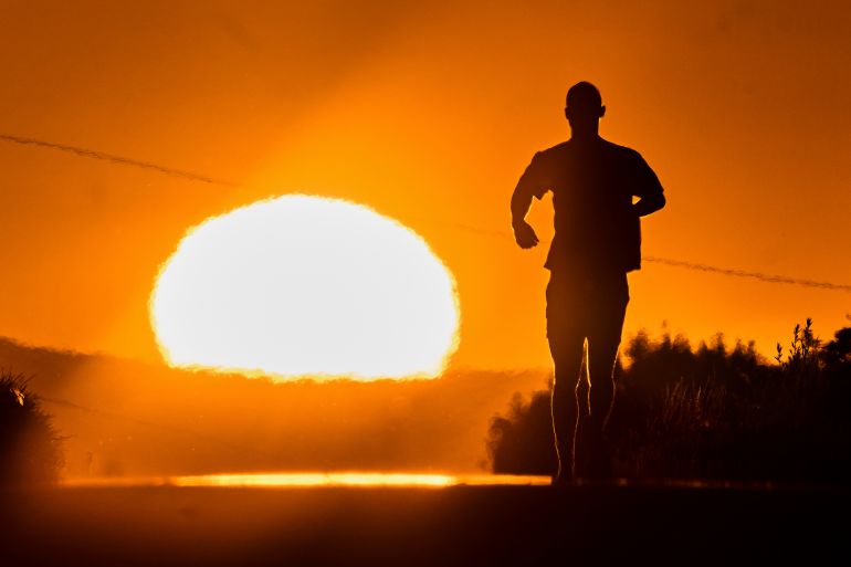 ap_686380deb54a2-1751351518 A man runs towards the rising sun on a small road in the outskirts of Frankfurt, Germany, Tuesday, July 1, 2025. (AP Photo/Michael Probst)