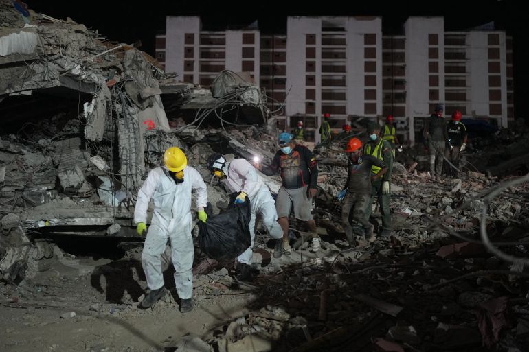 People carry a body recovered from a building that collapsed from earthquakes in La Guaira, Venezuela, Thursday, July 30, 2026. (AP Photo/Ariana Cubillos)