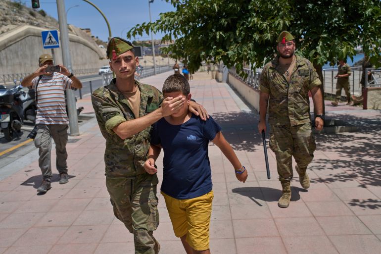 ap_6a75fb319c59a-1786116913 A 12-year-old unaccompanied minor who crossed into Spain is escorted by a Spanish soldier to the Spain-Morocco border from the Spanish enclave of Ceuta, Monday, Aug. 3, 2026. The forced deportation of the unaccompanied minor was stopped by a high-ranking official a few meters before the child reached the border after residents and journalists said the migrant was a minor. (AP Photo/Bernat Armangue)