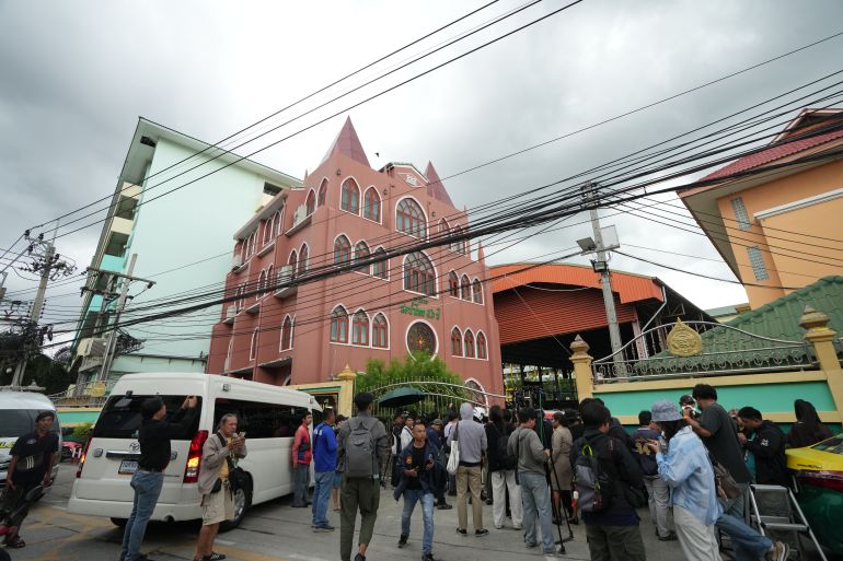 A crowd gathers outside a school where deaths and injuries were reported after a shooting in Thailand's Nonthaburi province, Friday, Aug. 7, 2026. (AP Photo/Sakchai Lalit)