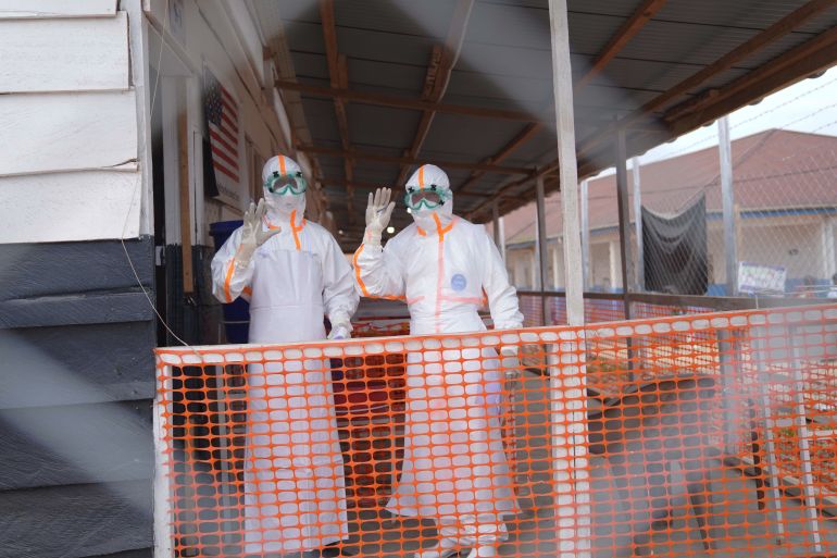 ap_6a7b0a0fcd857-1786448399 Health workers in protective gear wave inside an Ebola treatment centre in Bunia, Congo, Monday, Aug. 10, 2026. (AP Photo/Dieudonne Dirole)