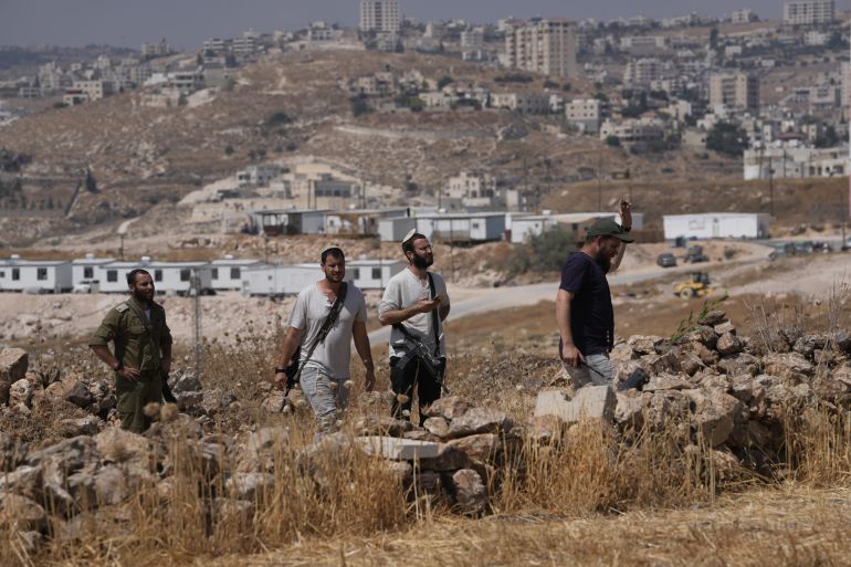 Israeli settlers gather from a nearby outpost, background, after Israeli and foreign peace activists took down a metal structure in the shape of a Star of David from atop a Palestinian structure during a protest in support of local landowners whose property is threatened with seizure by settlers, on the outskirts of the West Bank city of Beit Sahour, Friday, Aug. 14, 2026. (AP Photo/Mahmoud Illean)