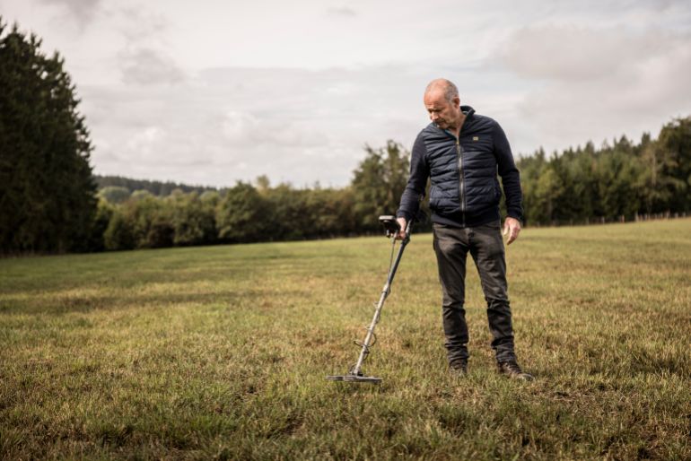 Bernard Collard runs a metal detector over a field in the Elsenborn area of Krinkelt, Belgium, Friday, Aug. 21, 2026. (AP Photo/Valentin Bianchi)