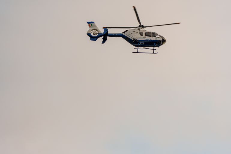 epa13158384 A Garda (Irish Police) helicopter flies over Casement Aerodrome in Baldonnel, County Dublin, Ireland, 09 August 2026, following the extradition of alleged crime boss Daniel Kinahan from the United Arab Emirates. An Irish government jet transported the 49-year-old from Dubai's Al Maktoum International Airport to the military airbase, where he was formally arrested and transferred to the Special Criminal Court in Dublin to face charges of directing an organized crime group. EPA/BARRY CRONIN