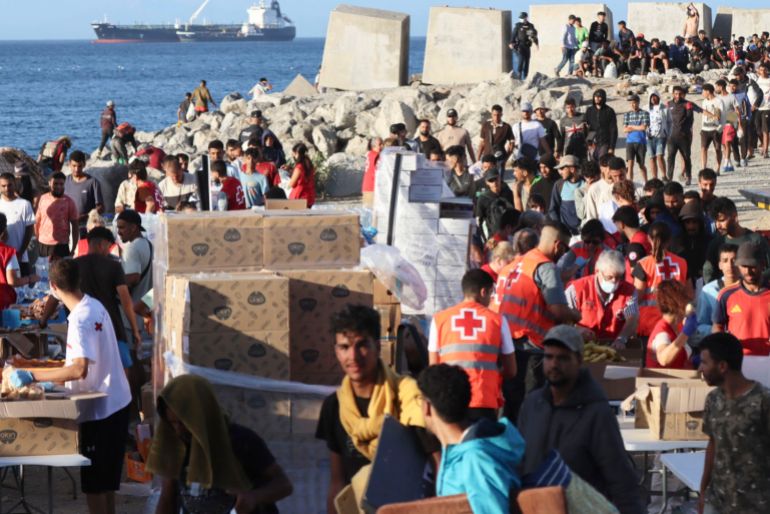 epa_6a91ca60534a-1787939424 epa13195367 Red Cross members distribute food to migrants at El Trampolin beach in Ceuta, 27 August 2026. Protests erupted in the Spanish enclave of Ceuta over the past two days, with residents demanding political resignations and the expulsion of migrants amid an escalating migration crisis. EPA/REDUAN