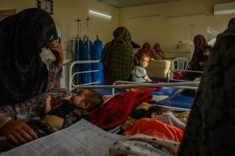 getty_6a8d7f4bea-1787658059 GHAZNI, AFGHANISTAN - AUGUST 23: Sediqa, 22, and her 11-month-old son Idris (L) and Namagey, 60, and her 4-year-old granddaughter Nazaka (C), who traveled three hours to reach the unit, are being cared for in a therapeutic feeding unit run by the French NGO Première Urgence Internationale inside the provincial hospital on August 23, 2025, in Ghazni, Afghanistan. The TFU now has to accommodate 38 patients in 20 beds with less staff. According to staff, the number of malnourished children is increasing following the closure of facilities due to the US funding cuts, including 10 mobile health teams in Ghazniand more in neighboring provincesthat were screening for malnutrition and providing therapeutic food. According to August data from the World Health Organization, 422 health facilities have been suspended or closed in Afghanistan since U.S. President Donald Trump issued an executive order to terminate USAID funding in February. Thirty of the closures have taken place in the Ghazni region, affecting more than 226,000 people. The humanitarian situation in Afghanistan has deteriorated in the wake of cuts by the US and other foreign aid sources, as vulnerable populations are left without access to life-saving medical care, including maternal and child health services. A recent study in the The Lancet medical journal has forecast that USAID funding cuts could result in the preventable deaths of more than 14 million people worldwide by 2030, including 4.5 million children under the age of five. (Photo by Elise Blanchard/Getty Images)