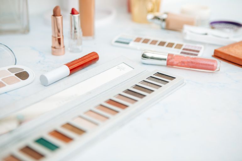 gettyimages-1203522463-1785958872 Pile of various cosmetics, make-up lie on wooden dressing table - stock photo