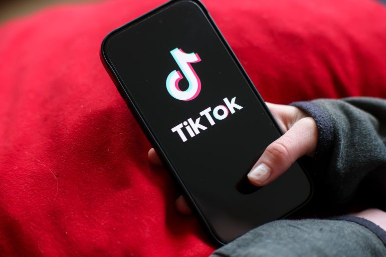 gettyimages-2261737986-1787330416 ILLUSTRATION - 17 February 2026, Saxony, Leipzig: A girl holds an iPhone 16 with the logo of the TikTok app on it. There is currently a debate in Germany about age limits for social media and possible stricter rules on cell phone use in schools. Photo: Jan Woitas/dpa (Photo by Jan Woitas/picture alliance via Getty Images)