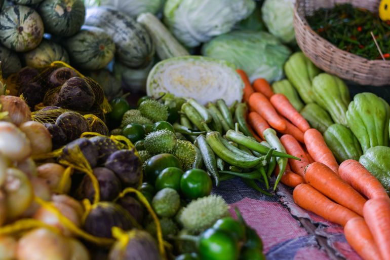 khd-1785500286 An array of fresh vegetables displayed at an outdoor market stall, showcasing a variety of produce.
