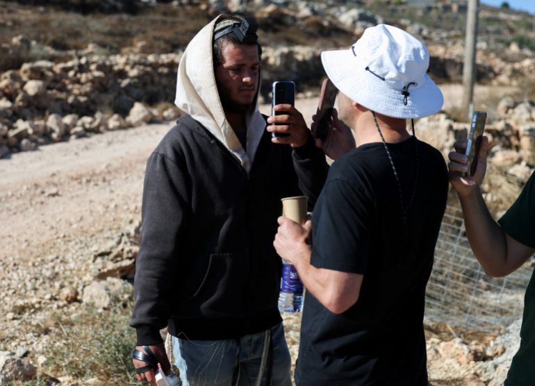 Palestinian-American Loui Ridi (R), whose house was encircled by militant settlers for over a week, films an Israeli settler (L) who entered his property in Qusra, Israeli-occupied West Bank, August 18, 2026. REUTERS/Ammar Awad