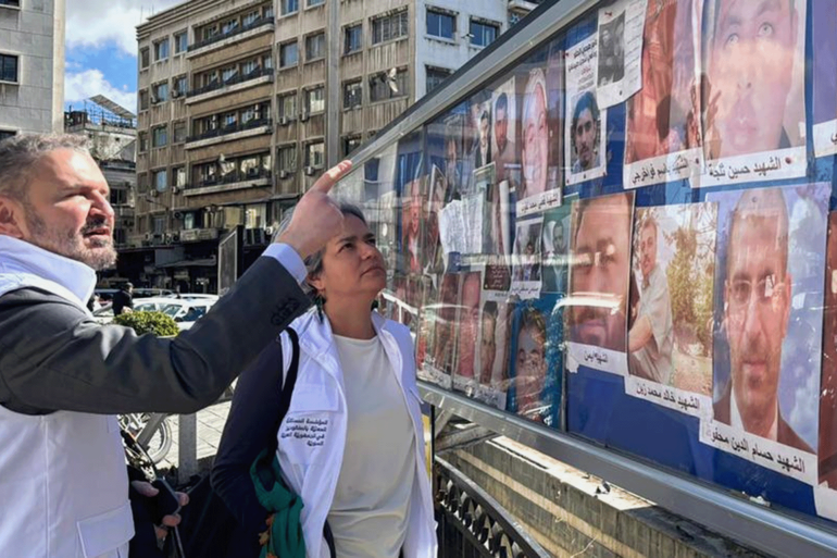 pic-9988553-1785165067 شخصان يتفقدان لوحة عليها صور أشخاص مفقودين في ساحة المرج بدمشق مركز أخبار الأمم المتحدة لزيارةرئيس المؤسسة المستقلة للمفقودين في سوريا سجن صيدنايا وساحة المرجة بدمشق