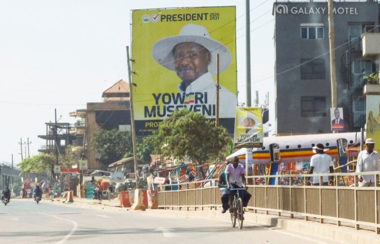 reuters_696aa2ca-1768596170 A man cycles past a campaign billboard of Uganda's President and the leader of the ruling National Resistance Movement (NRM) party, Yoweri Museveni, following the general elections in Kampala, Uganda January 16, 2026. REUTERS/Thomas Mukoya