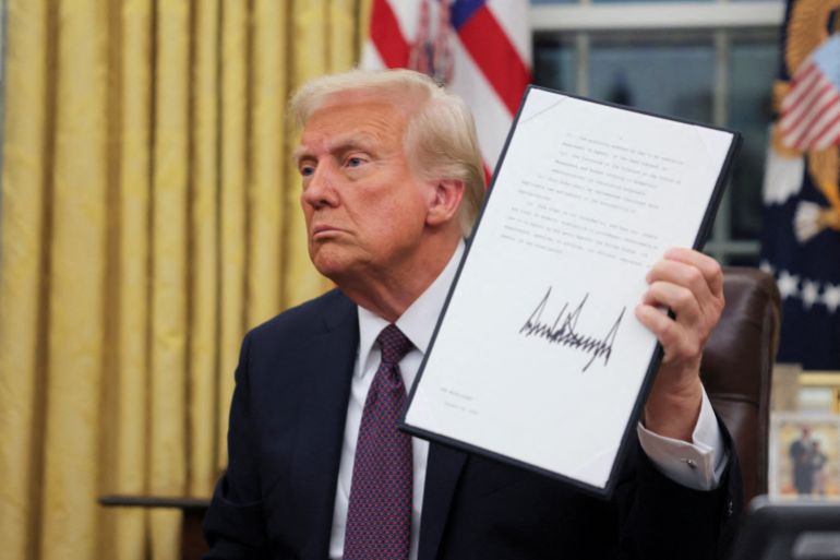 reuters_6a652ae1-1785015009 FILE PHOTO: U.S. President Donald Trump holds a document on the day he issues executive orders and pardons for January 6 defendants in the Oval Office at the White House on Inauguration Day in Washington, U.S., January 20, 2025. REUTERS/Carlos Barria/File Photo