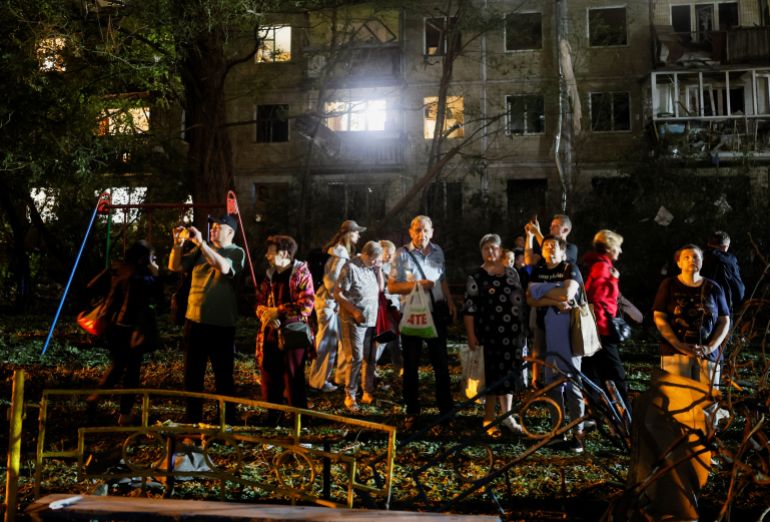People stand together at the site of an apartment building hit by a Russian missile strike, amid Russia's attack on Ukraine, in Kyiv, Ukraine, August 1, 2026. REUTERS/Gleb Garanich