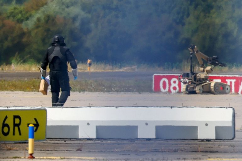 reuters_6a75ed4f-1786113359 A police officer in protective clothing walks next to an explosive-disarming robot (EOD) at Leipzig/Halle Airport in Schkeuditz, Germany, August 5, 2026, after the police said explosives experts examined a drone found near a runway, and after a DHL cargo aircraft hit an unknown object as it was climbing away from the airport overnight, prompting an unscheduled landing in Hanover, according to a source familiar with the incident. REUTERS/Axel Schmidt TPX IMAGES OF THE DAY