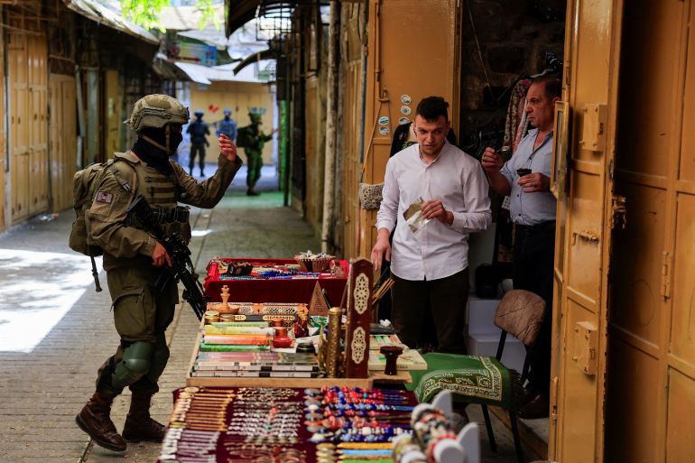 reuters_6a778f42-1786220354 An Israeli soldier orders Palestinian shopkeepers to close their stall, during Israeli settlers' weekly tour in Hebron, in the Israeli-occupied West Bank, July 25, 2026. REUTERS/Mussa Qawasma