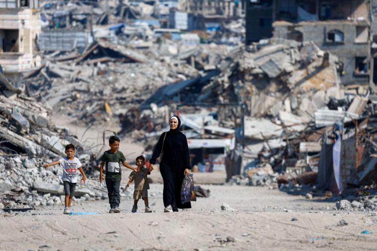 Palestinians walk past the rubble of residential buildings destroyed during the war, in Gaza City, August 15, 2026. REUTERS/Mahmoud Issa TPX IMAGES OF THE DAY