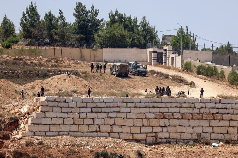 sd-1786603653 Israeli soldiers stand guard next to settlers (L) in front of the Palestinian houses in the village of Qusra, south of Nablus, in the occupied West Bank, on August 12, 2026. Israel has occupied the West Bank since 1967, but in recent years the number of settlements in the Palestinian territory -- which are illegal under international law -- has soared. Excluding east Jerusalem, more than 500,000 Israelis live in settlements in the West Bank, home to around three million Palestinians. (Photo by Zain JAAFAR / AFP)