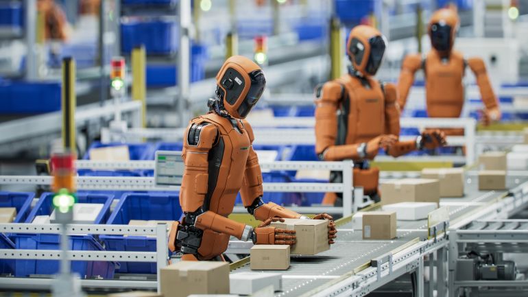 shutterstock_2644805399-1780830882 Autonomous AI-Enabled Humanoid Robot Working at Fulfillment Center. He is Moving Boxes and Sorting Packages. Automated Warehouse or Logistics Center with General Purpose Humanoid Robots