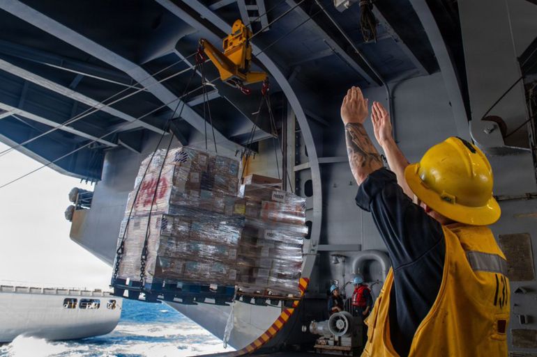 ss-15-1787206768 Pallets of supplies are delivered to the USS Theodore Roosevelt in a replenishment-at-sea during the RIMPAC exercises in July 2026. Aircraft carriers typically spend months at sea at a time, requiring a complicated logistical effort to resupply them. (US Navy/Mass Communication Spc. 3rd Class Alexia Mezick)