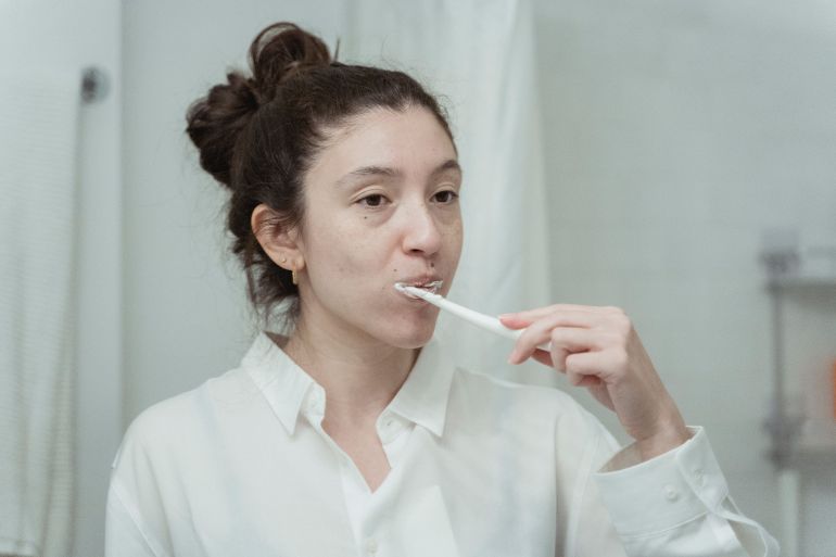 tnzyf-1785760312 Young woman practicing dental hygiene by brushing her teeth in the morning.