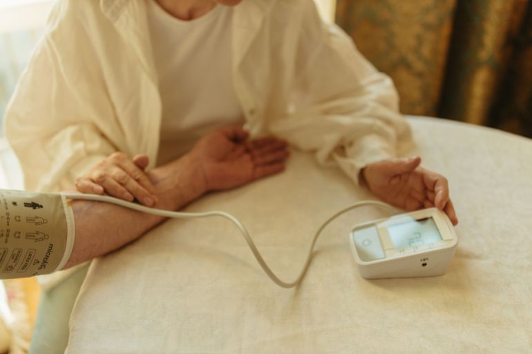 088852-1787581859 A senior adult checking their blood pressure with a digital monitor at home.