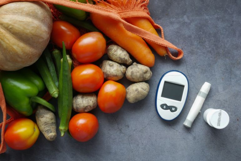 11423202-1789155166 A flat lay of diabetes equipment alongside fresh vegetables promoting healthy lifestyle.