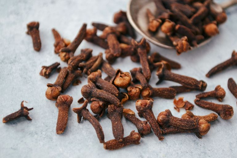 142752-1788446122 A close-up image of aromatic dry cloves scattered on a spoon over a gray surface.