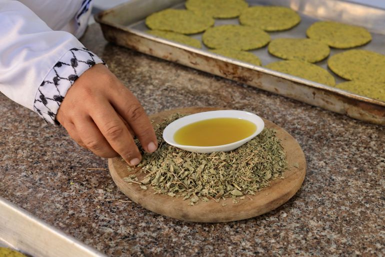 2-1790182960 فلسطين- غزة- حي الرمال- أكاديمية سمايل كيتشن، 22/09/2026 وفي استعادة تطبيقية للموروث الغذائي الفلسطيني، تولّى الشيف نبيل الشوّاف، 65 عامًا، داخل مطبخ "سمايل كيتشن"، إعداد مائدة قوامها الزعتر؛ استحضر فيها وصفات متوارثة كالمسفّن والمناقيش والمطبّق، ووسّع حضورها باجتهادات طهوية معاصرة فرضتها ندرة المكونات إسراء الرّملي- خاص الجزيرة نت..