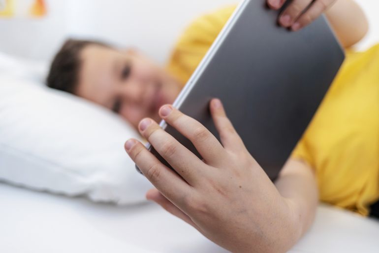 Young boy enjoys screen time in his bed, using a tablet computer to explore the digital world. Child using gadget, education and development. by Jelena Stanojkovic @ادوبي ستوك
