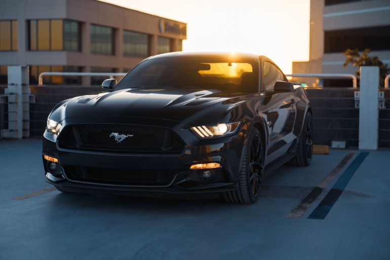 Elegant black sports car in urban parking, captured beautifully at sunset.