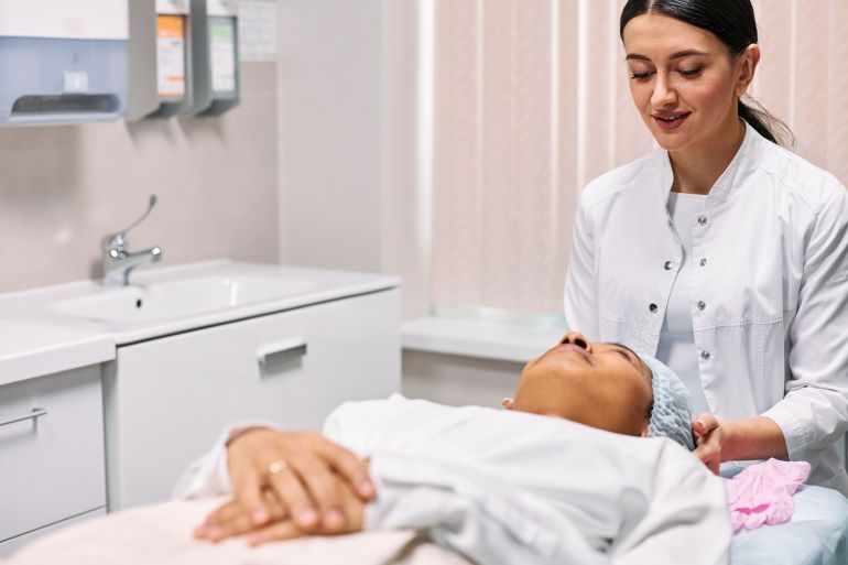 81072-1787507711 A beautician providing skincare treatment to a woman in a clinic setting, focusing on care and relaxation.