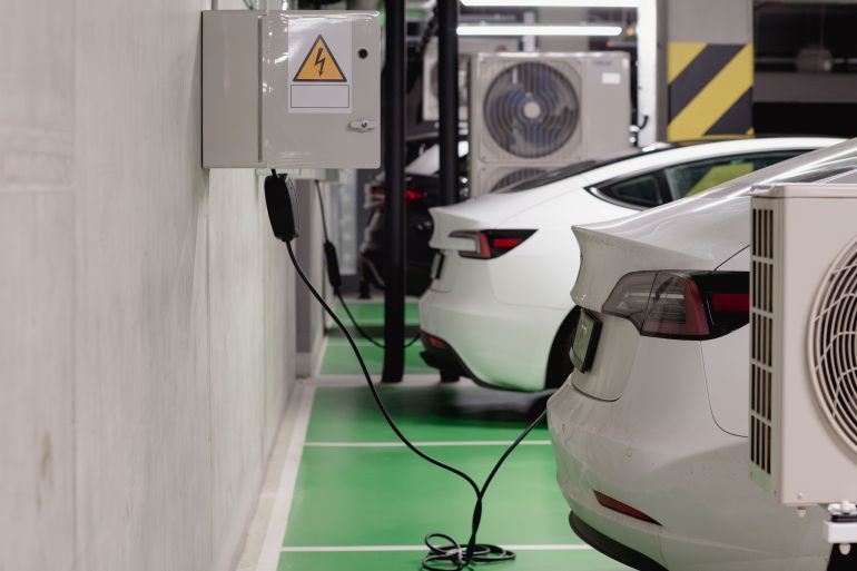 851165-1787843013 Electric vehicles charging at an indoor station in a modern underground garage.
