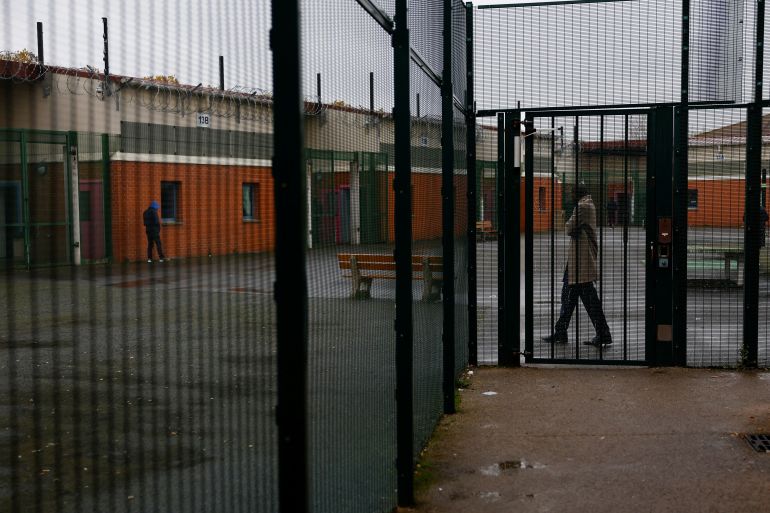 Migrants stand behind barriers in the courtyard of a detention centre, where migrants are sent to await deportation, in Mesnil-Amelot near Paris, France, November 18, 2024. French rights group La Cimade said it tracked 341 deportation orders issued last year as a result of new legislation. The group said it supported 191 individuals last year at the Mesnil-Amelot detention centre, near Charles-de-Gaulle airport, who would have previously been protected. Of those, 35 were deported, and 24 released due to courts overturning deportation orders, it said.  REUTERS/Stephanie Lecocq SEARCH "GNAGO FRANCE DEPORTATIONS" FOR THIS STORY. SEARCH "WIDER IMAGE" FOR ALL STORIES.