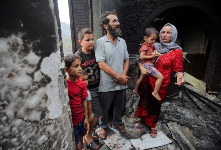 Amar Belkati, a 57-year-old farmer, stands with his wife Souhila and their children inside their burnt house, following a wildfire in Bejaia, Algeria July 25, 2023. REUTERS/Ramzi Boudina