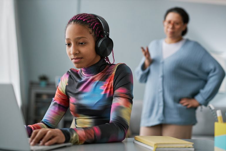 adobestock_565371787-1784823150 Portrait of black teenage girl using laptop with headphones and ignoring mother in background المصدر: أدوبي ستوك