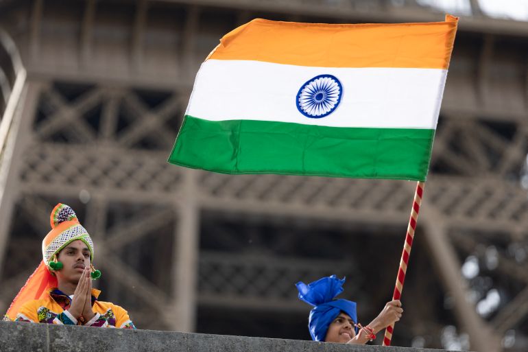 Members of the Bochasanwasi Akshar Purushottam Swaminarayan Sanstha (BAPS) Hindu community wave an Indian flags =during a religious ceremony in front of the Eiffel Tower before a ceremonial river parade on the river Seine in Paris on September 3, 2026.